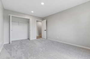 Unfurnished bedroom featuring light carpet and a closet