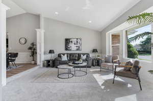 Living room featuring high vaulted ceiling, ornate columns, and hardwood / wood-style flooring