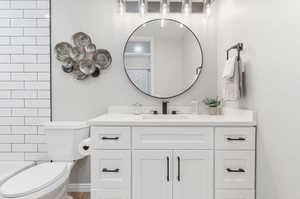 Full bathroom with tile walls, hardwood / wood-style flooring, toilet, vanity, and bathtub / shower combination