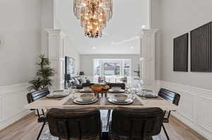 Dining area with decorative columns, light wood-type flooring, and a chandelier