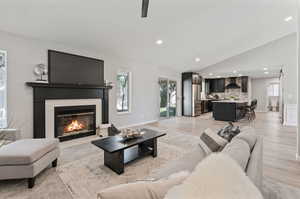 Living room featuring light wood-type flooring, vaulted ceiling, plenty of natural light, and a tile fireplace