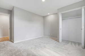 Unfurnished bedroom featuring light carpet and a closet