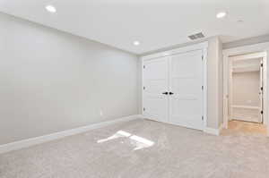 Unfurnished bedroom featuring a closet and light colored carpet