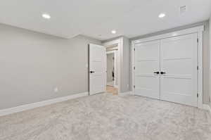 Unfurnished bedroom with light carpet and a closet