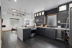 Kitchen featuring wine cooler, appliances with stainless steel finishes, hanging light fixtures, sink, and dark hardwood / wood-style floors