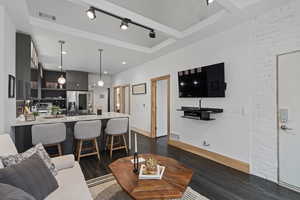 Living room featuring dark hardwood / wood-style flooring, track lighting, and brick wall