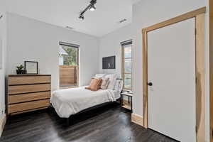 Bedroom with dark hardwood / wood-style floors and rail lighting