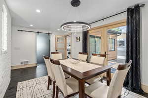 Dining area with french doors, a barn door, hardwood / wood-style floors, and an inviting chandelier