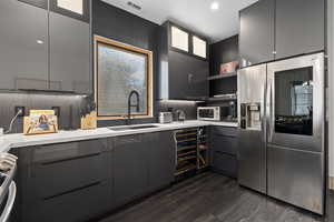 Kitchen featuring sink, stainless steel refrigerator with ice dispenser, stove, tasteful backsplash, and dark hardwood / wood-style flooring