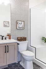 Bathroom with toilet, tile patterned floors, vanity, and a shower with shower door