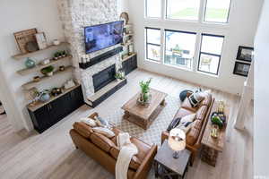 Living room featuring light hardwood / wood-style flooring, a stone fireplace, and a healthy amount of sunlight