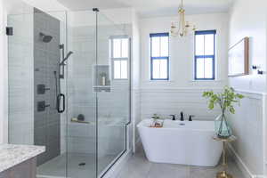 Bathroom with a notable chandelier, vanity, separate shower and tub, and tile patterned flooring