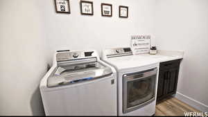 Washroom featuring light wood-type flooring, washing machine and dryer, and cabinets