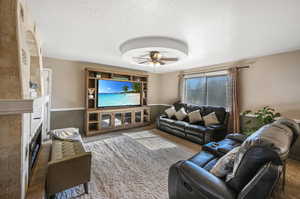 Carpeted living room featuring ceiling fan and a textured ceiling