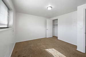 Unfurnished bedroom featuring a textured ceiling, carpet, and a closet