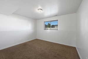 Unfurnished room featuring a textured ceiling and carpet