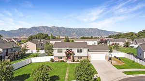 View of front of home with a front lawn, a mountain view, and a garage