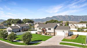 View of front of house featuring a front lawn, a mountain view, and a garage