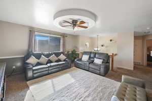 Carpeted living room featuring a textured ceiling and ceiling fan