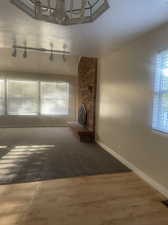 New carpet in living room with fireplace, an inviting chandelier, rail lighting, wood-type flooring.