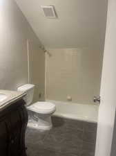 Full bathroom with vanity, tiled shower / bath, tile patterned flooring, and toilet