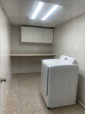 Laundry area featuring cabinets, washer / dryer, and light tile patterned floors