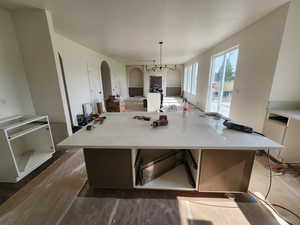 Kitchen featuring wood-type flooring, light stone countertops, a kitchen island, and pendant lighting