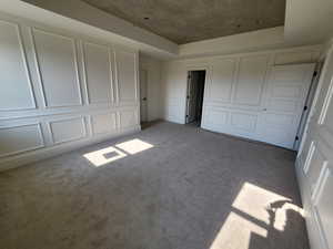 Master bedroom with light carpet and a tray ceiling