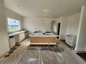 Kitchen with large island, large plaster venthood to be installed