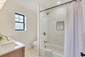 Full bathroom with shower / bath combo with shower curtain, tile patterned floors, vanity, and toilet