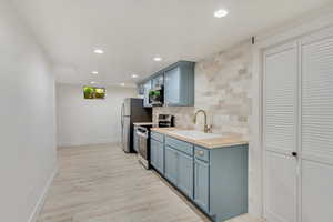 Kitchen with stainless steel appliances, wood counters, decorative backsplash, sink, and light hardwood / wood-style floors