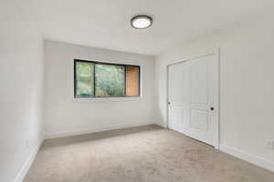 Unfurnished bedroom with light colored carpet and a closet