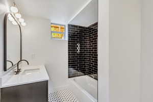 Bathroom featuring tile patterned floors, vanity, a textured ceiling, and tiled shower / bath