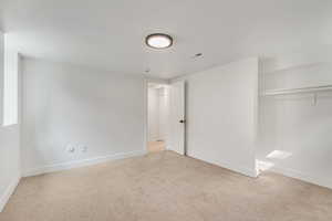 Unfurnished bedroom featuring light colored carpet and a closet