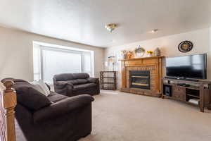 Carpeted living room with a textured ceiling and a brick fireplace