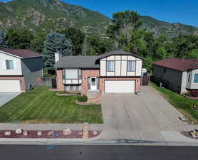 View of front of property with a mountain view, a front yard, and a garage