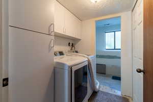 Laundry room with independent washer and dryer, cabinets, and a textured ceiling