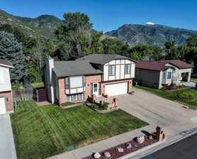 View of front facade with a front yard, a mountain view, and a garage