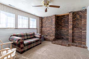 Living room with ceiling fan, carpet, and brick wall