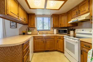 Kitchen featuring white appliances, sink, kitchen peninsula, and light tile patterned floors