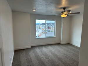 Carpeted empty room featuring ceiling fan and a textured ceiling