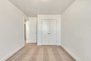 Unfurnished bedroom with light carpet and a closet