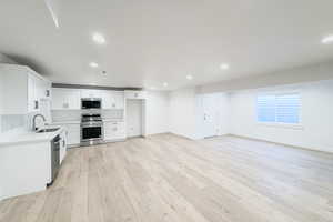 Kitchen featuring white cabinetry, stainless steel appliances, light hardwood / wood-style floors, and sink