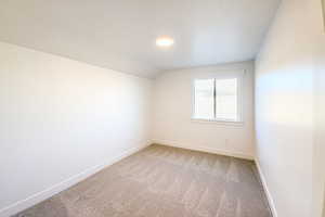 Carpeted spare room with vaulted ceiling