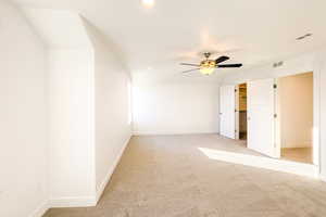 Unfurnished bedroom with ceiling fan, light colored carpet, and a spacious closet