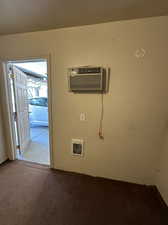 Carpeted spare room/office space in 1/2 of 3rd car garage space with ceiling fan and a wall mounted AC and heater