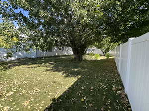 View of fenced back yard with mature trees