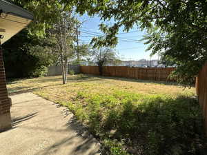 View of backyard featuring fully fenced, mature trees, fully automated sprinkling system