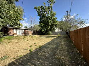 View of backyard featuring fully fenced, mature trees, fully automated sprinkling system