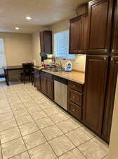 Kitchen with dishwasher, sink, a textured ceiling, and light tile patterned floors